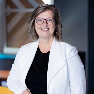 Luann Feehan Sq1 A headshot of a woman smiling with a black shirt on underneath a white blazer. She is sitting in a chair.